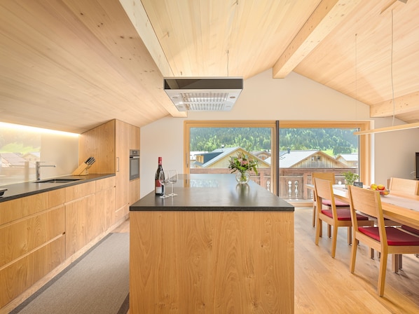 A modern kitchen with wooden cabinets, a central island, and a dining area with wooden chairs and a table.