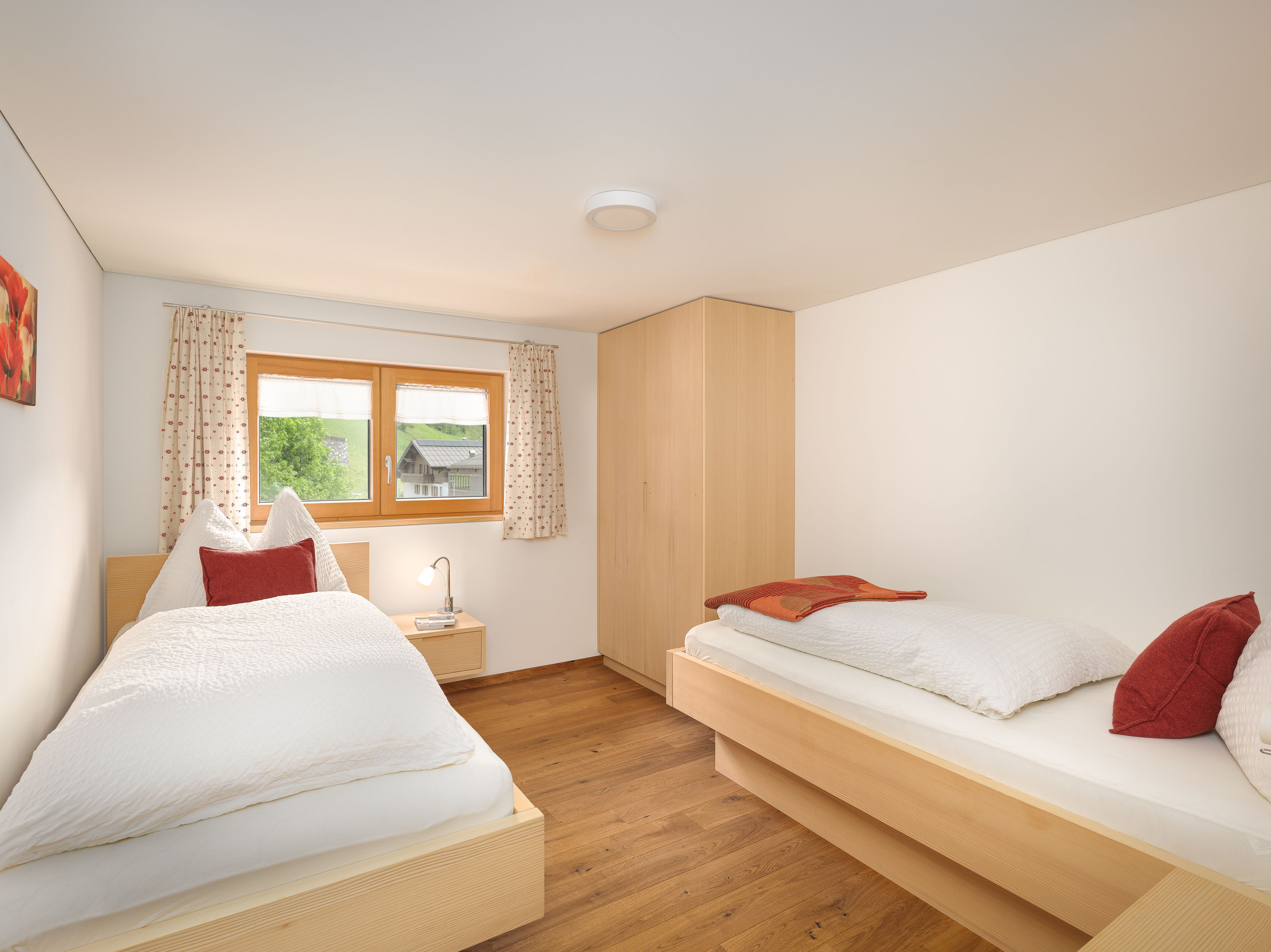 Ein Schlafzimmer mit zwei Betten, einem Fenster, einem Nachttisch und Holzböden.