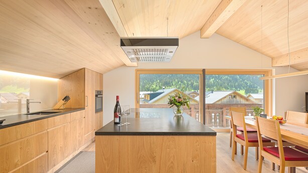 Una cucina moderna con mobili in legno, un'isola centrale e un'area pranzo con sedie e tavolo in legno.