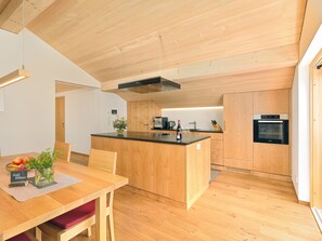 Eine moderne Küche mit Holzschnitzereien, einer zentralen Kochinsel und einem eingebauten Backofen.