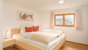 Una camera da letto con un letto, un comodino, una lampada, una finestra con tende e un quadro appeso al muro.