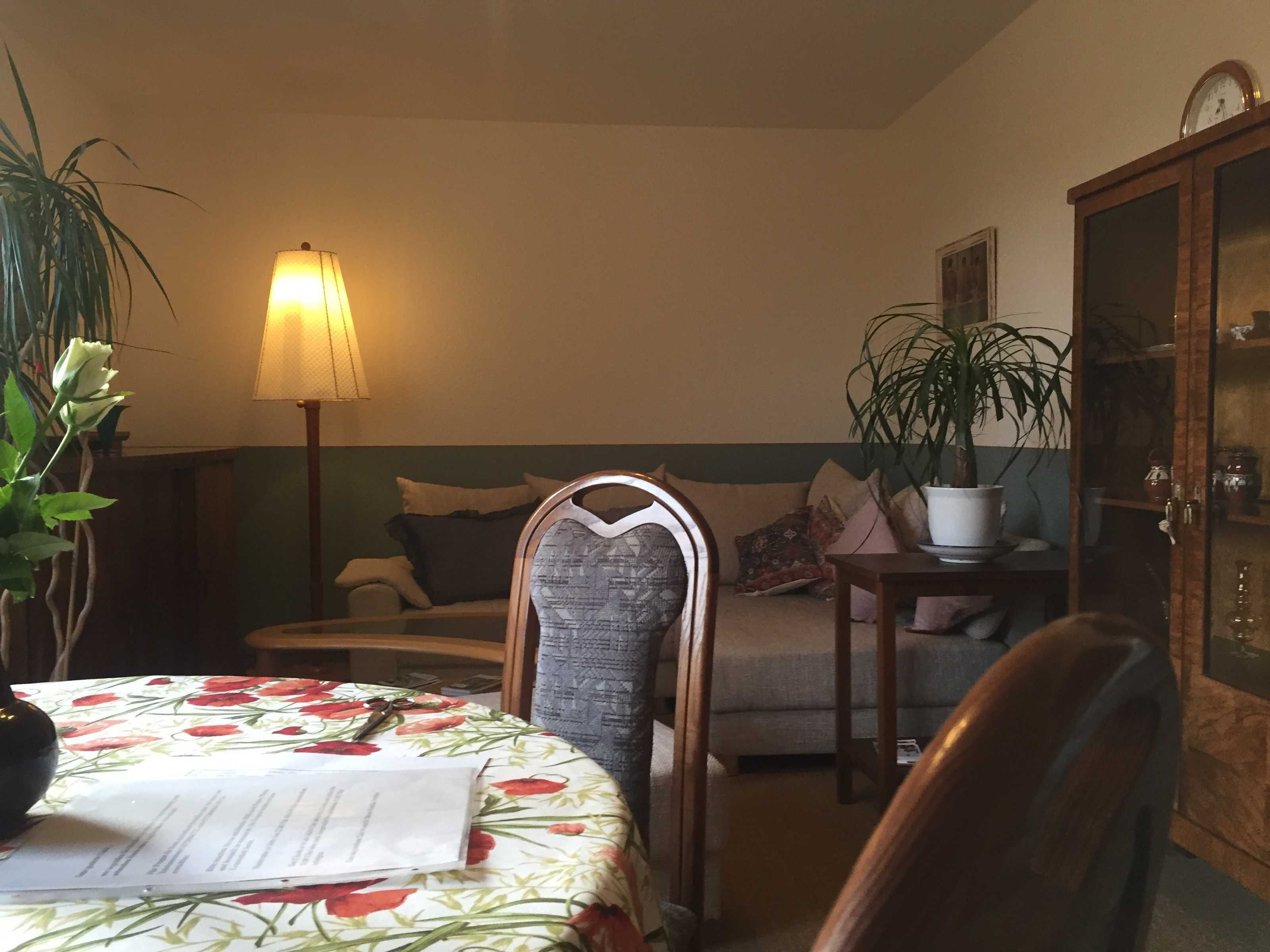 Una sala acogedora con una mesa de comedor, un sofá, una lámpara y un armario.