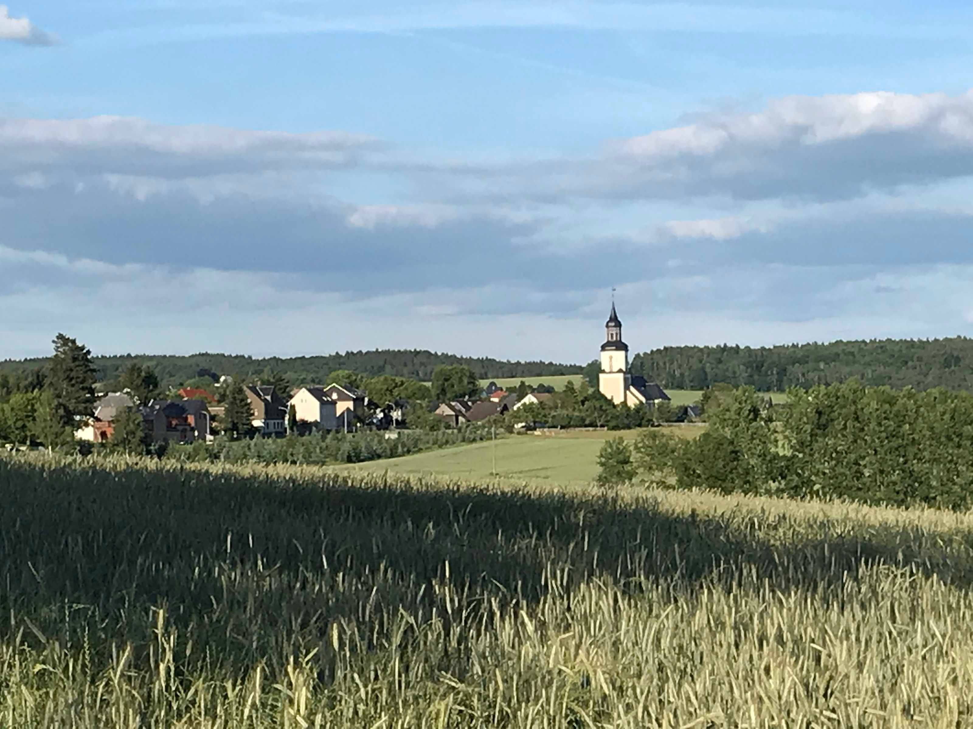 Paisagem rural com igreja, casas e campos.