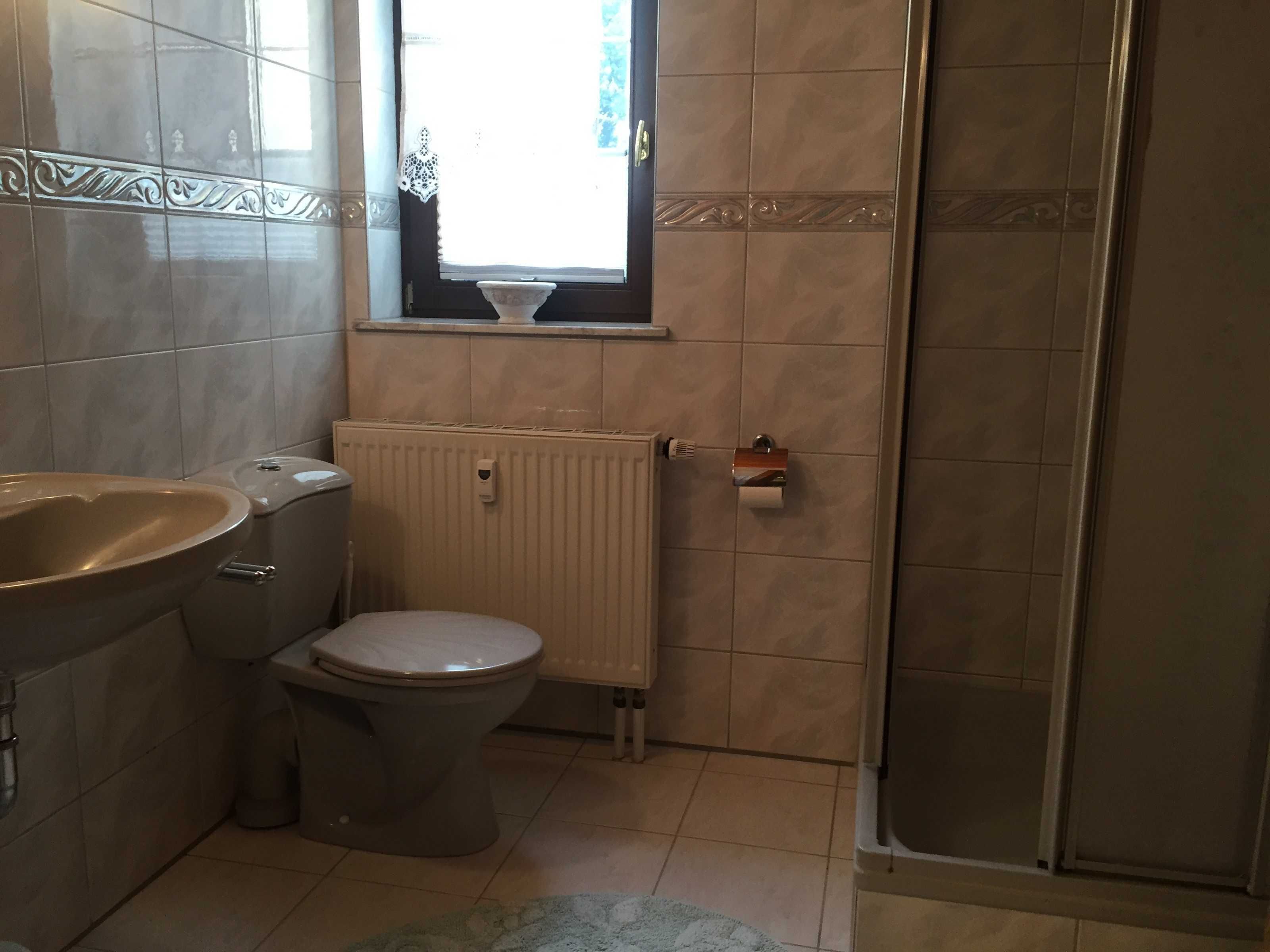 A bathroom with a bathtub, toilet, and a window.