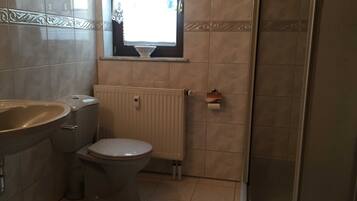 A bathroom with a bathtub, toilet, and a window.
