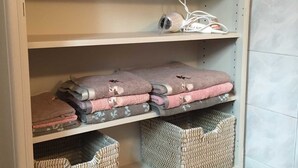 Une étagère blanche, décorée de motifs ouvragés, avec des paniers en osier et des serviettes pliées.