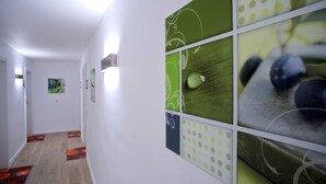Un pasillo con una lámpara, un tapete estampado y una pared decorada con cuadros.