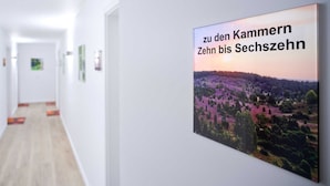 A hallway with a poster on the wall, a wooden floor, and white walls.