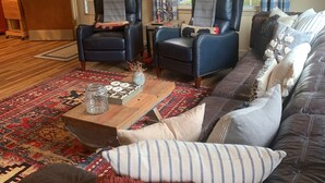 Een gezellige woonkamer met een grote bank, twee fauteuils, een salontafel en een tapijt met een patroon.