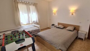 A bedroom with two beds, a foosball table, and two wall-mounted lamps. - Family home with sea view near St-Florent (Rutali)