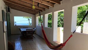 A kitchen with a tiled floor, a dining table with chairs, a refrigerator, and a hammock. - Family home with sea view near St-Florent (Rutali)