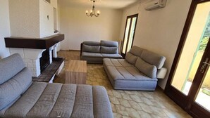 A living room with a fireplace, two sofas, a coffee table, and a chandelier. - Family home with sea view near St-Florent (Rutali)