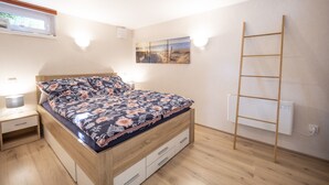 A bedroom with a wooden bed, a nightstand, a wall-mounted ladder, and a painting. - Ihr Ruhepol im Naturschutzgebiet am Ihlsee! Wellness für die Seele! (Bad Segeberg)