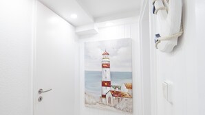 A hallway with a white door, a painting of a lighthouse, and a rope tied to the wall. - Ihr Ruhepol im Naturschutzgebiet am Ihlsee! Wellness für die Seele! (Bad Segeberg)
