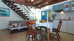 Un espace repas comprenant une table en bois, des chaises et un escalier menant à un niveau supérieur.