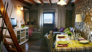 A cozy dining area with a table set for two, a stone wall, and a view through a window. - Alojamiento Rural con Encanto La Casona del Piquero (Lastres)