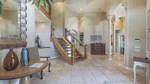 A spacious foyer with a wooden staircase, a round table with a vase, and a large mirror. - ROYAL PALM HOUSE - Luxury Style 3 Bedroom Home On Captiva With Private Pool (Captiva)