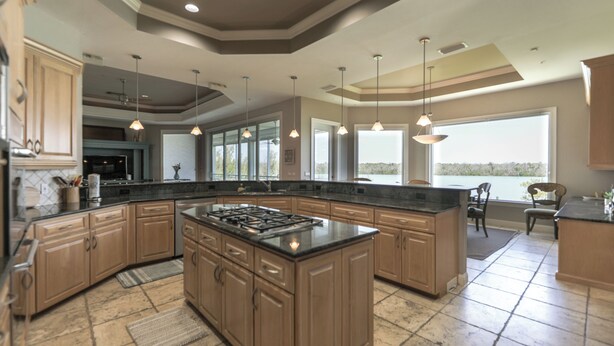 A spacious kitchen with a large island, wooden cabinets, and pendant lighting. - ROYAL PALM HOUSE - Luxury Style 3 Bedroom Home On Captiva With Private Pool (Captiva)