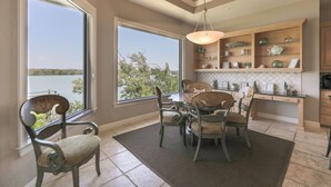 A dining area with a view of the lake, a chandelier, and wooden shelves with decorative items. - ROYAL PALM HOUSE - Luxury Style 3 Bedroom Home On Captiva With Private Pool (Captiva)