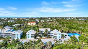 A resort with multiple blue buildings, a pool, and a view of the ocean. - Seashells #39 |July & August Discounts! 3 Night Min. Stays! (Sanibel)
