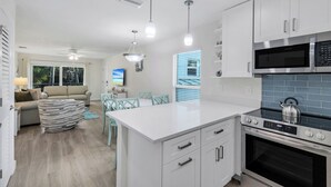 A modern kitchen with white cabinets, a stainless steel stove, and a large island. - Seashells #39 |July & August Discounts! 3 Night Min. Stays! (Sanibel)