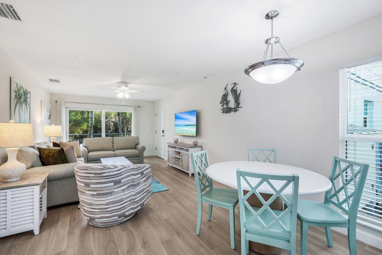 A spacious living room with a sofa, a dining table with chairs, a TV, and a ceiling fan.