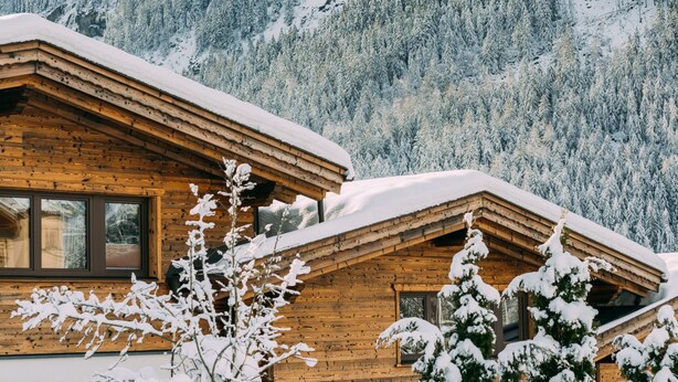 A wooden cabin with a sloped roof, surrounded by snow-covered trees and mountains. - Chalet Häuser (oetz)