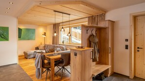 A cozy living area with a wooden ceiling, a sofa, a dining table, and a bench. - Chalet Häuser (oetz)