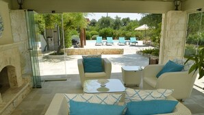 Un espace extérieur aménagé, abrité et doté de mobilier en osier, offrant une vue sur le jardin.