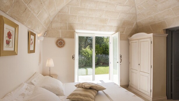 Une chambre à coucher avec un grand lit, une armoire et une porte donnant sur un jardin.