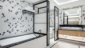 A modern bathroom with a large bathtub, a glass shower enclosure, and a vanity with a mirror.