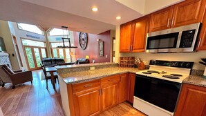 A modern kitchen with wooden cabinets, a stainless steel microwave, and a white stove.
