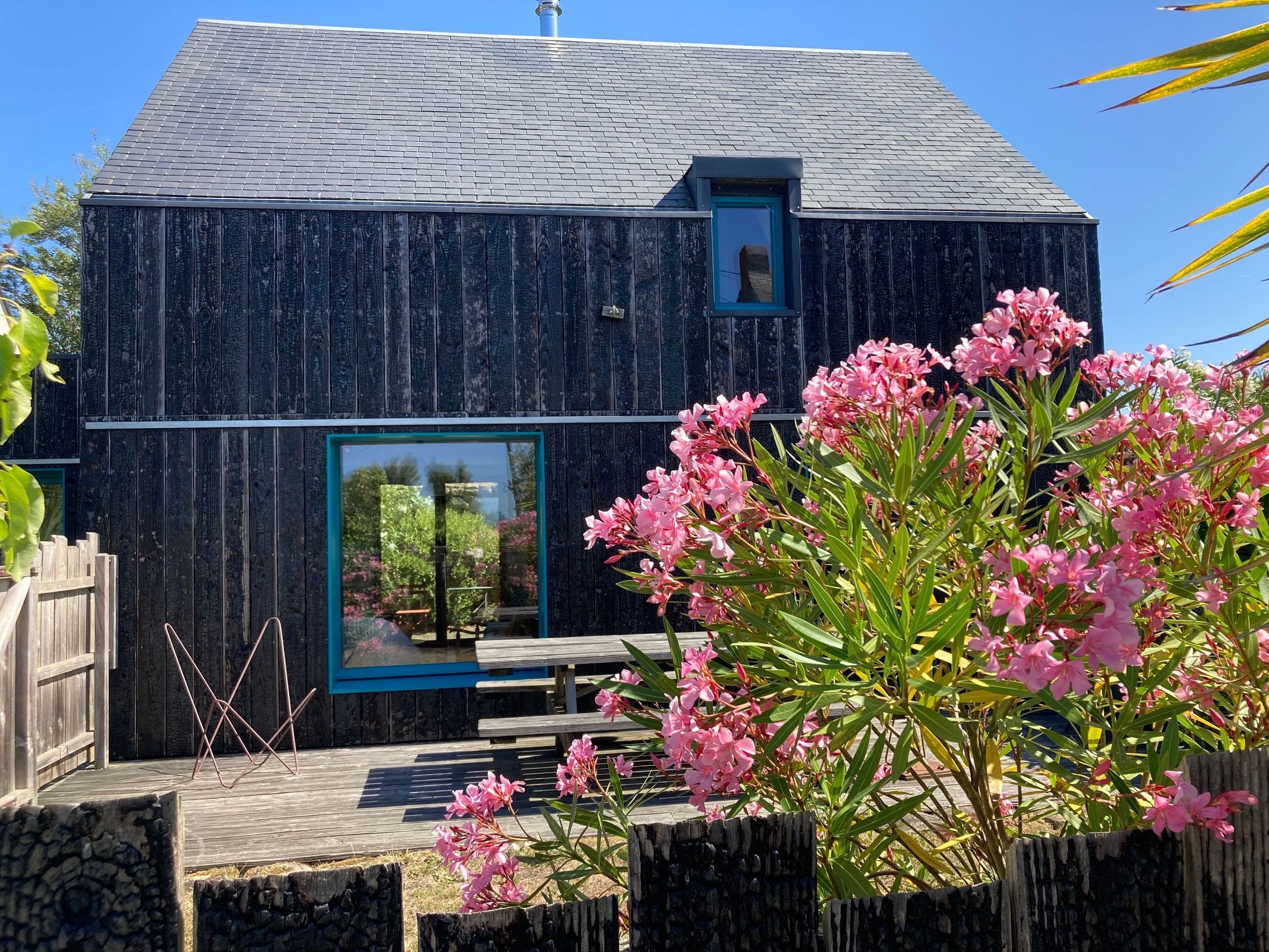 A rustic wooden building with a sloped roof, a small window with a blue frame, and a wooden deck with benches.