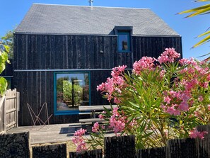 A rustic wooden building with a sloped roof, a small window with a blue frame, and a wooden deck with benches.
