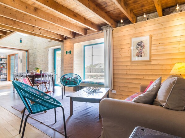 A cozy room with wooden walls, a sofa, a table, and a chair.