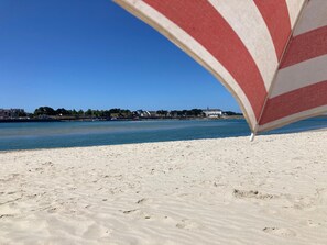 A beach with a clear view of the water and buildings in the background.
