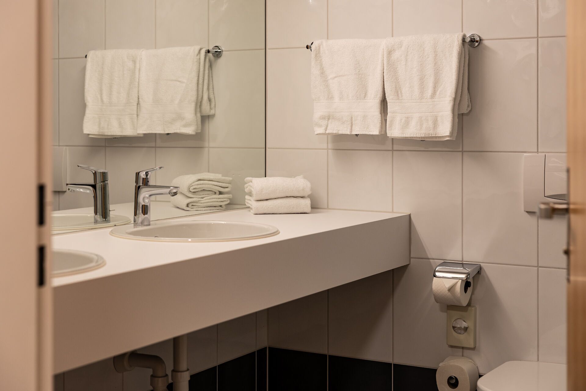 Un baño moderno con dos lavabos, un espejo y un inodoro.