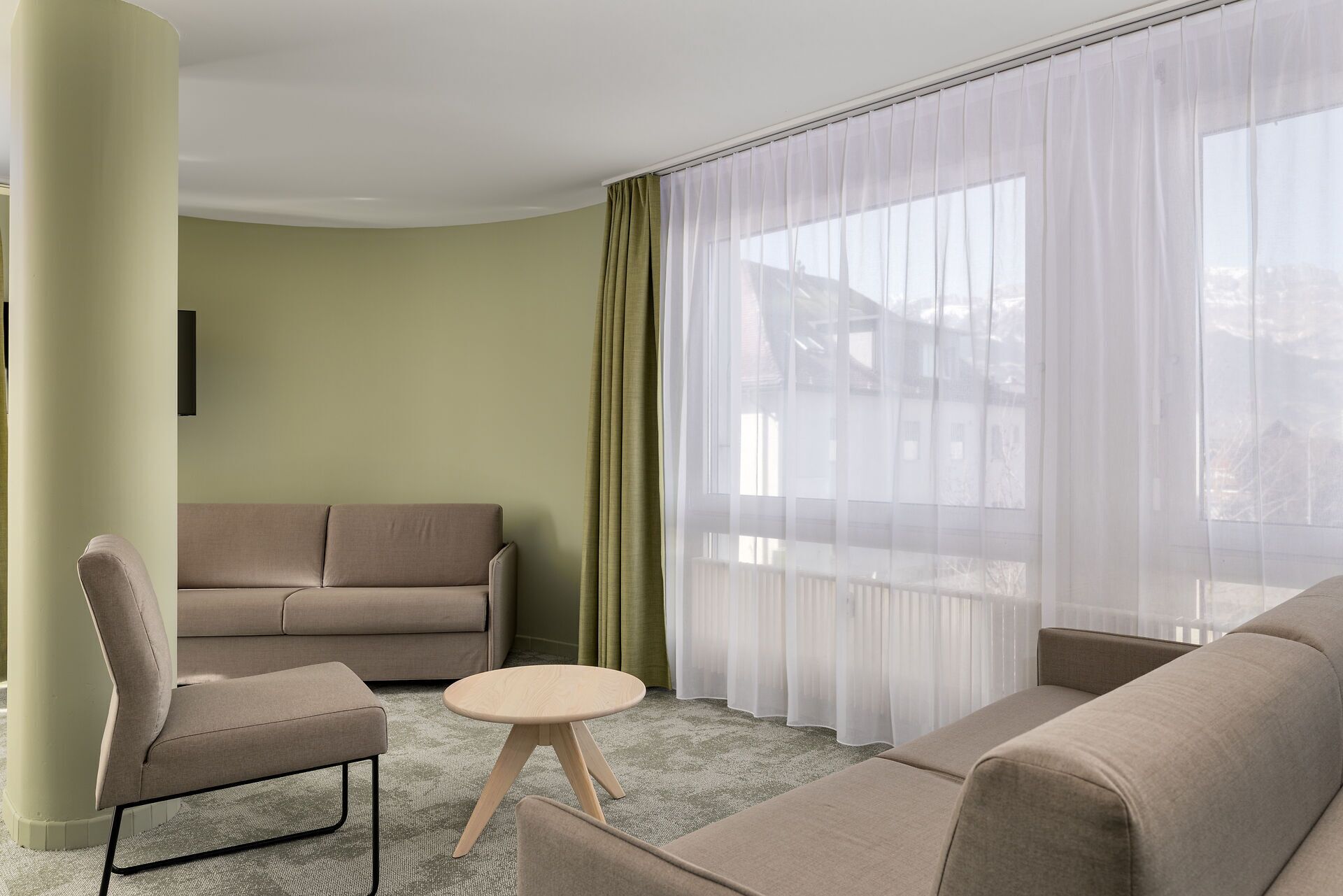 Ein modernes Wohnzimmer mit einem beigen Sofa, einem kleinen runden Tisch und einem Sessel.