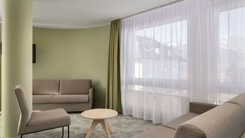 Ein modernes Wohnzimmer mit einem beigen Sofa, einem kleinen runden Tisch und einem Sessel.