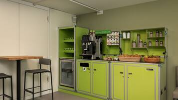 A kitchenette with a coffee station, a refrigerator, and a seating area with two chairs.