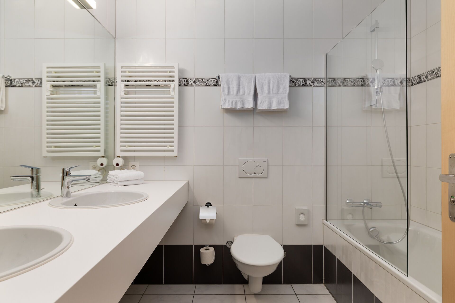 A modern bathroom with two sinks, a toilet, and a glass-enclosed shower.