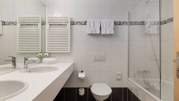 A modern bathroom with two sinks, a toilet, and a glass-enclosed shower.