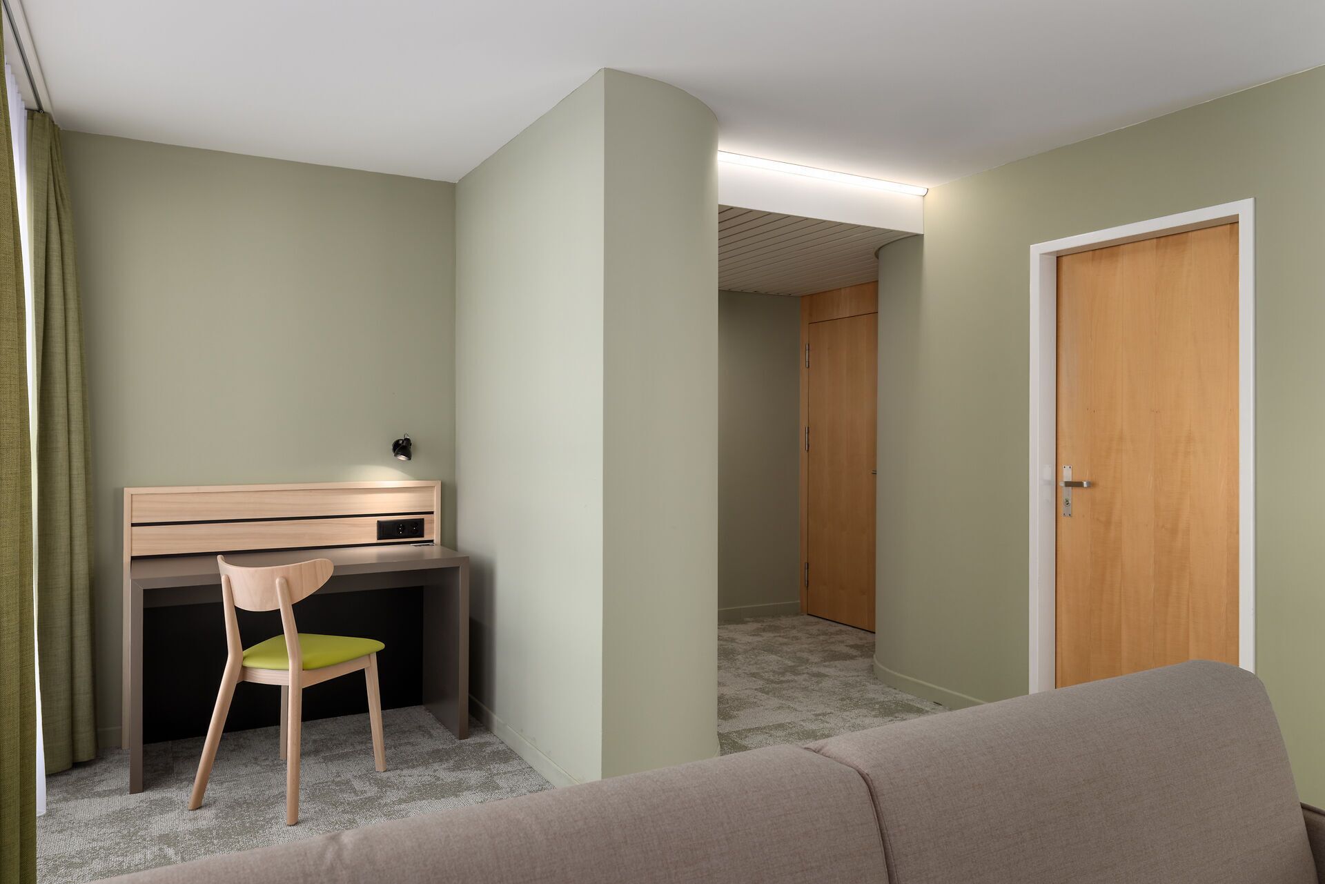 Ein Zimmer mit Schreibtisch, Stuhl und Tür.