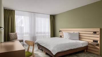 Ett hotellrum med en säng, sängbord, ett skrivbord och en stol.