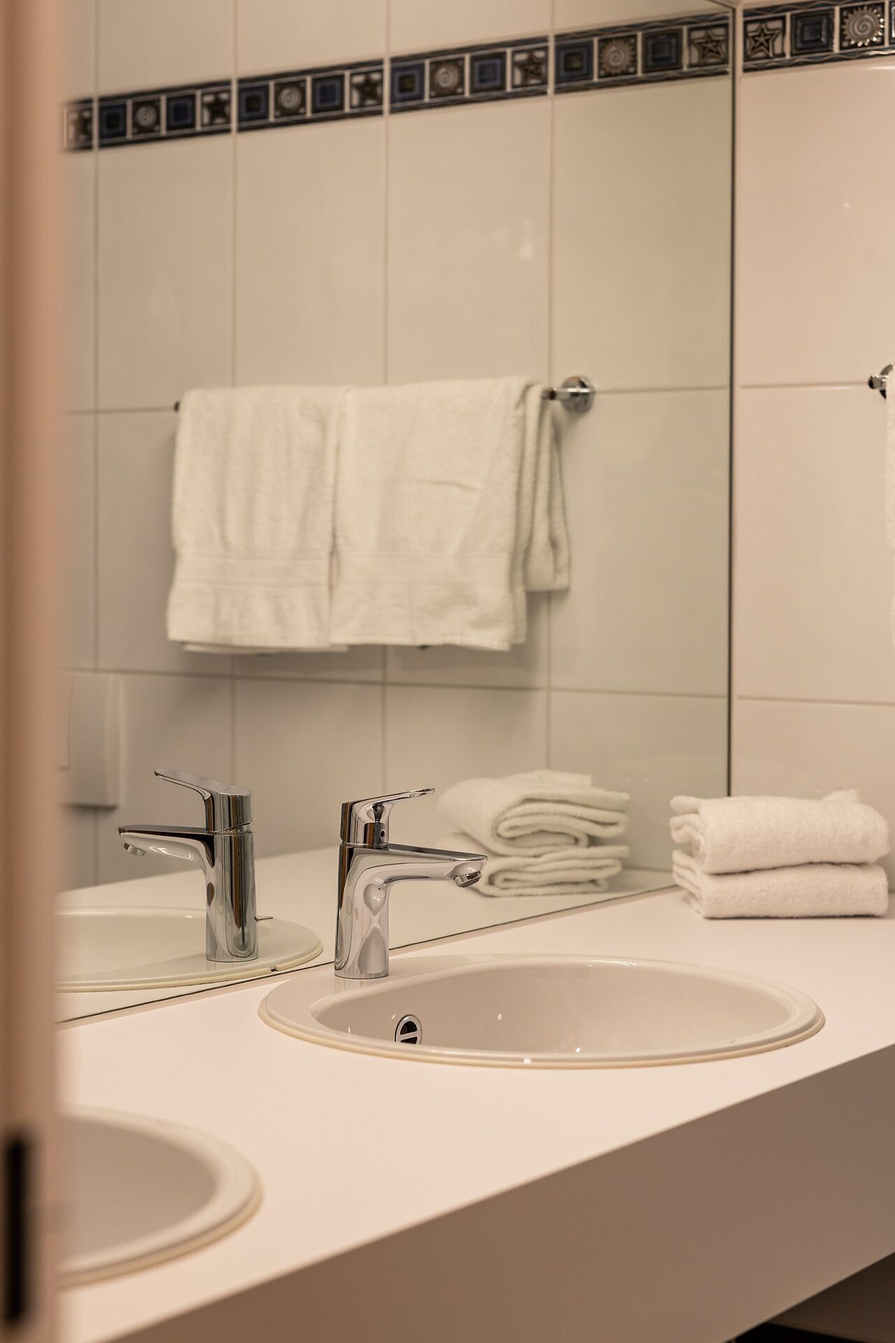Une salle de bain avec deux lavabos, un miroir et un porte-serviettes.