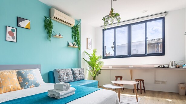 A modern bedroom with a large bed, a small kitchenette, and a view of the city through large windows. - Sleepier Multi-Minsu Tainan (Tainan)