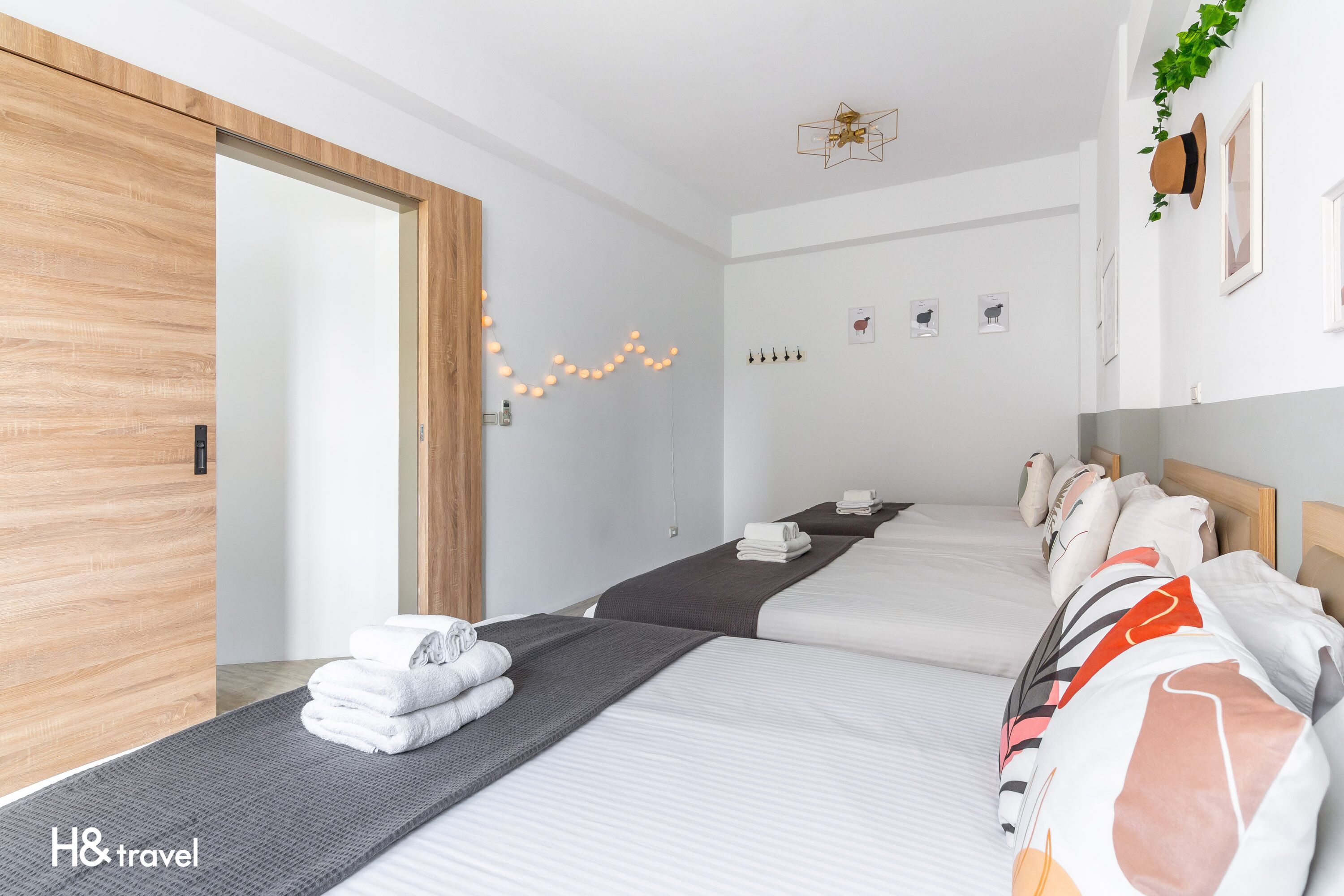 Hotelkamer met twee bedden, een houten deur, een plafondlamp en een aan de muur bevestigde plant.
