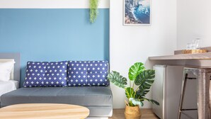 A modern living room with a grey sofa, a wooden coffee table, a potted plant, and a kitchen area with a refrigerator and bar stools. - Sleepier Multi-Minsu Tainan (Tainan)