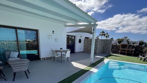 Una casa moderna con piscina, area relax all'aperto e un muro in pietra.