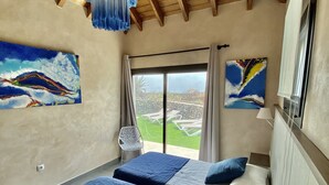 Una camera da letto con due letti, un lampadario, opere d'arte, una finestra con tende e vista sull'esterno.